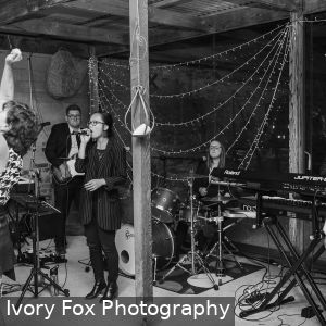 Yen Stender singing and Marly Cruse playing guitar and Natalie Cruse playing drums and Emile Ryjoch playing saxophone for wedding at White Hill Estate South Australia on 20th October 2018